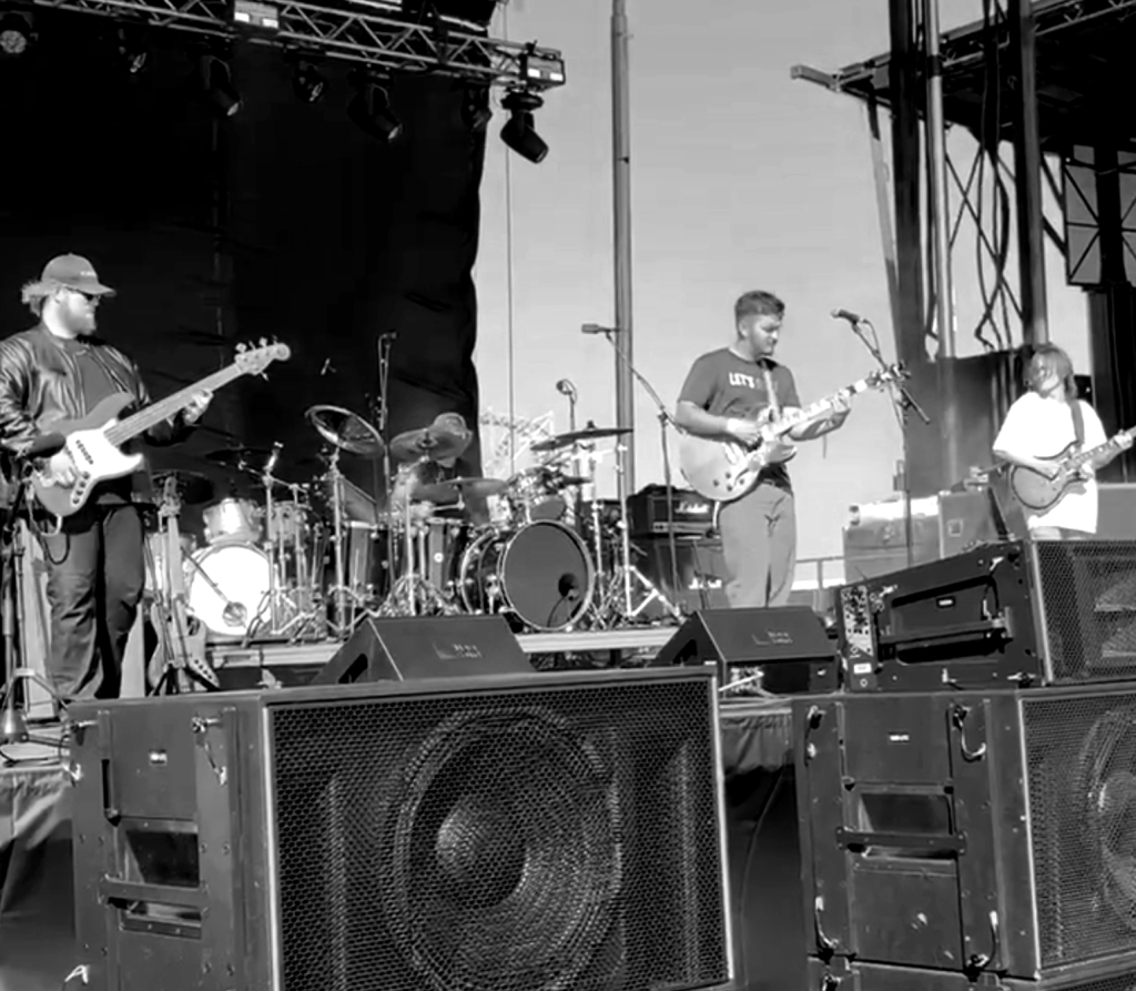 A band performing on an outdoor festival stage.